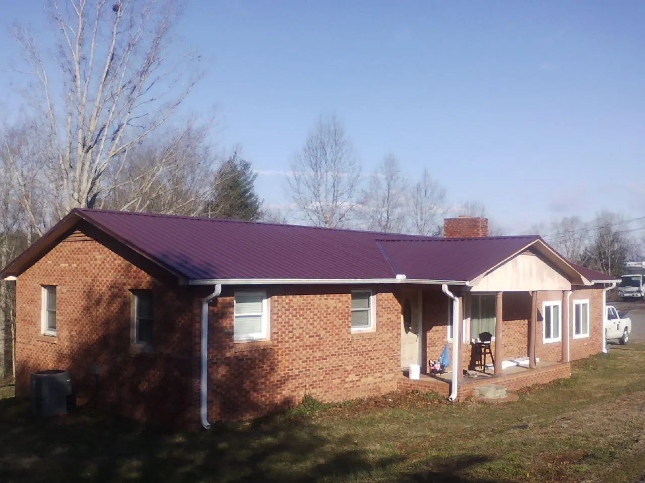 Burgundy metal roof on a brick ranch home with a new addition in Hankamer