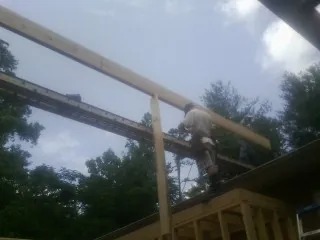 Carpenter setting a ridge beam over a new addition frame — Ice Dam Removal by Roofing Brothers in Hankamer