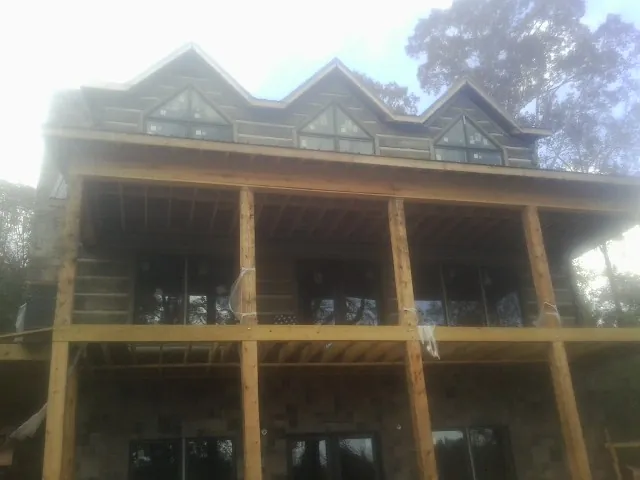 Dormers and porch framing on a large log home under construction — Roof Coating work by our crew in Hankamer