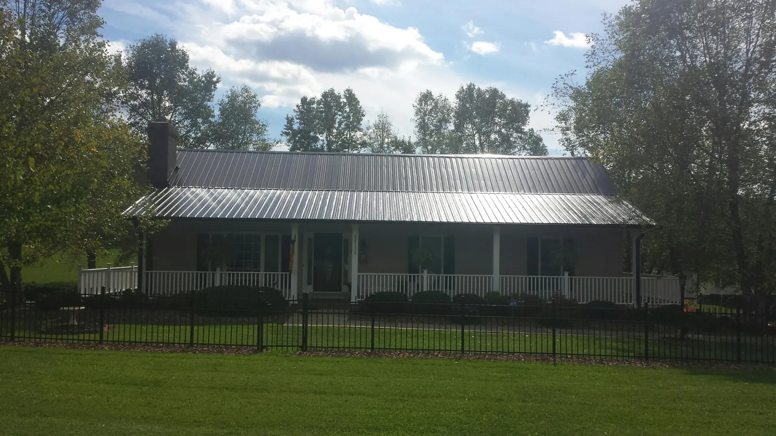 Gray metal roof on a brick ranch with a full width front porch — Gutter Guard Installation work by our crew in Hankamer